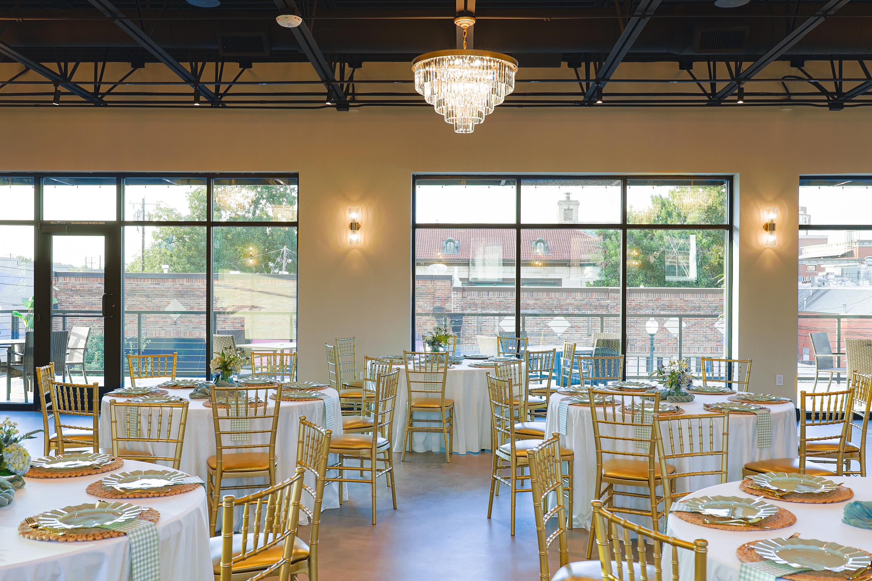 Round tables set beside the windows in the sunlit main hall at The Chestnut Hall