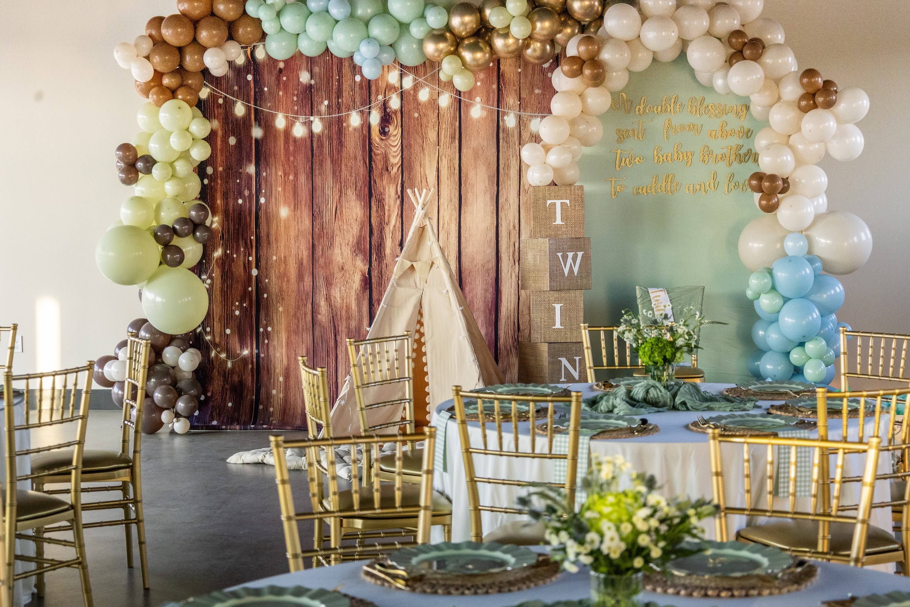 Rustic woodland teepee backdrop and gold Chiavari chairs at a baby shower